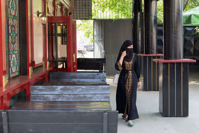 Muslim woman walking through an empty street cafe before opening.