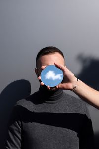 Midsection of man holding crystal ball against sky