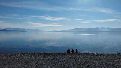 Rear view of people on beach against sky