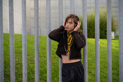 Young woman standing against fence