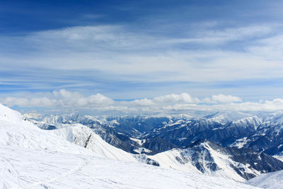 Snow-covered mountain tops in the clouds. in the background is a blue cloudy sky