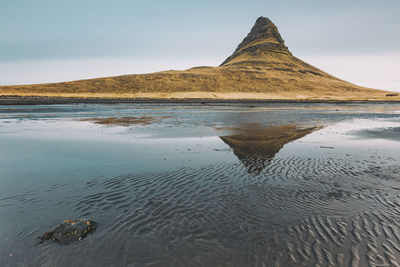 Reflection of mountain in sea against sky