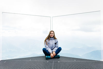 Portrait of woman sitting on mountain against sky