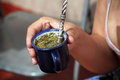Close-up of woman hand holding drink on a summer afternoon. mate is a sudamerican traditional drink 