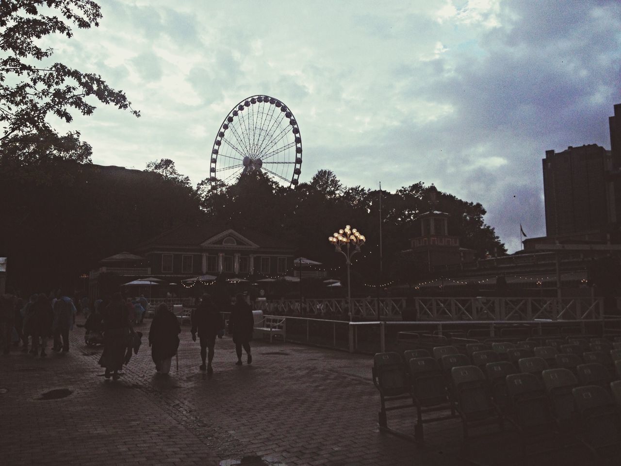 sky, ferris wheel, architecture, built structure, arts culture and entertainment, amusement park, amusement park ride, building exterior, leisure activity, cloud - sky, men, large group of people, lifestyles, person, low angle view, city, silhouette, dusk, cloud