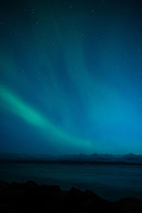 Scenic view of sea against sky at night with aurora borealis