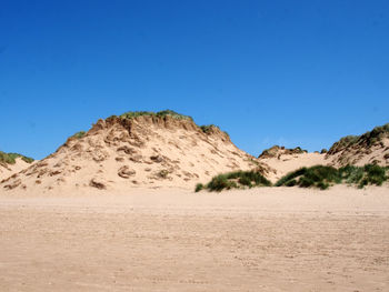 Scenic view of desert against clear blue sky