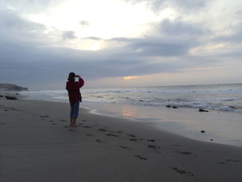 Full length of man on beach against sky during sunset