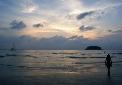 Silhouette man standing on beach against sky during sunset