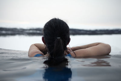 Woman bathing in cold lake in winter