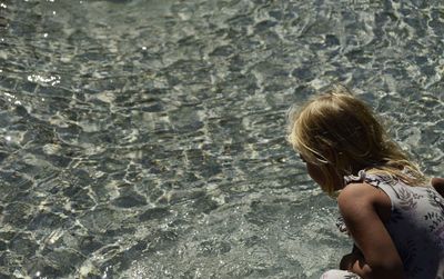 High angle view of girl looking into sea during sunny day