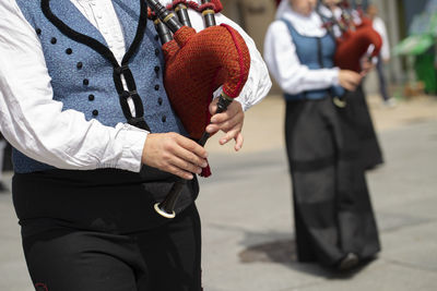 Midsection of musician playing bagpipe on street in city