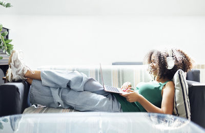 Side view of woman sitting on bed at home