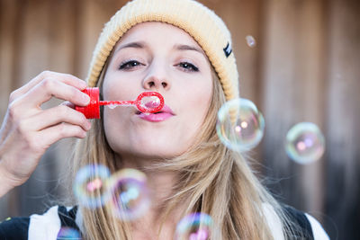 Close-up portrait of a beautiful young woman holding bubbles