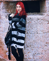 Portrait of woman standing against wall