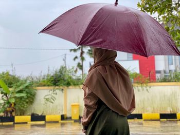 Rear view of hijab girl with umbrella on street