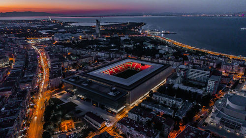 High angle view of illuminated city buildings by sea against sky