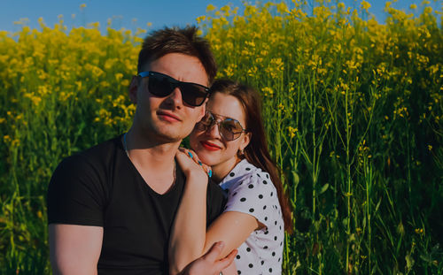 Portrait of young woman standing amidst yellow flowering plants on field