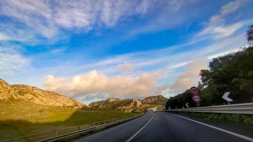 Road leading towards mountains against sky