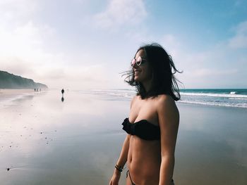 Woman standing at beach against sky