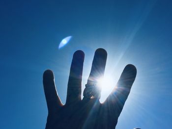 Low angle view of hand against sky during sunny day