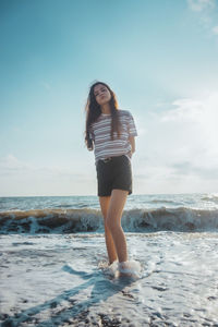 Full length of young woman standing on beach