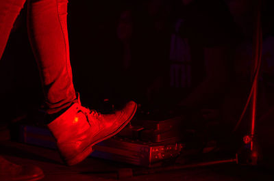 Low section of person wearing red shoes at night