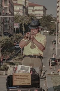 Senior man playing trumpet while standing on street