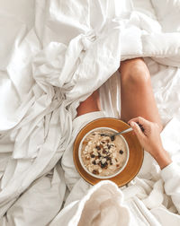 High angle view of  woman holding bowl of oatmeal porridge in bed