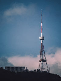 Low angle view of communications tower and buildings against sky