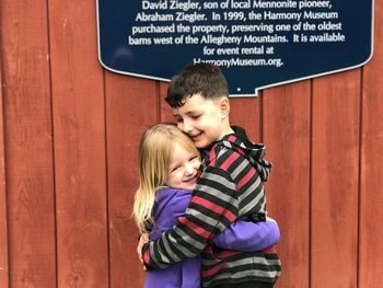 Happy siblings standing against blue wall