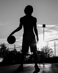 Rear view of silhouette woman standing against sky