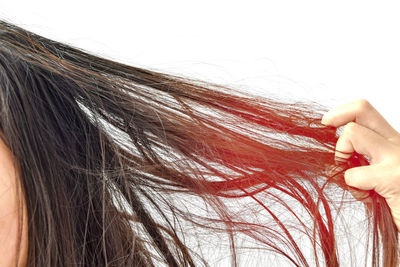 Cropped image of woman with hand tangled hair against white background