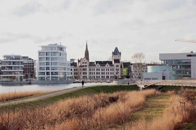 Buildings in city against cloudy sky