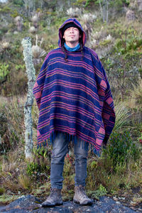 Colombian native american man in traditional clothing standing in forest