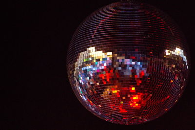 Low angle view of illuminated lighting equipment hanging against black background