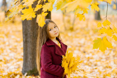 Autumn street portrait of a beautiful happy child girl walking in a park or forest in a coat