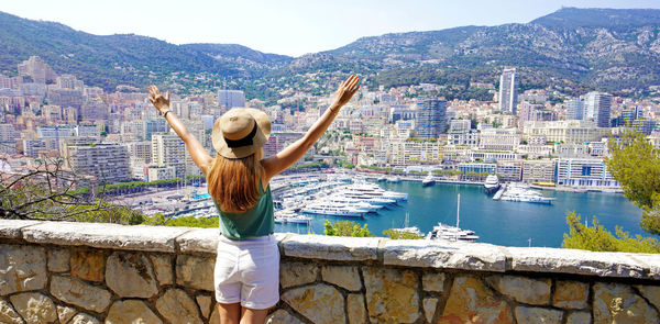 Panoramic banner view of young woman raising arms on monte-carlo cityscape and marina in monaco