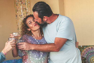 Couple kissing while toasting against wall