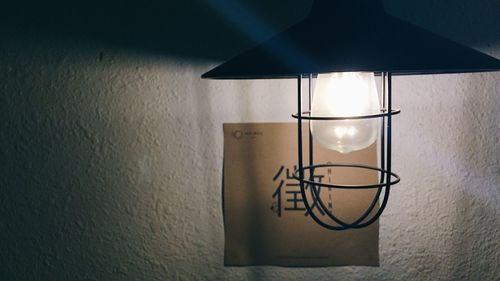 Close-up of illuminated light bulb hanging at home