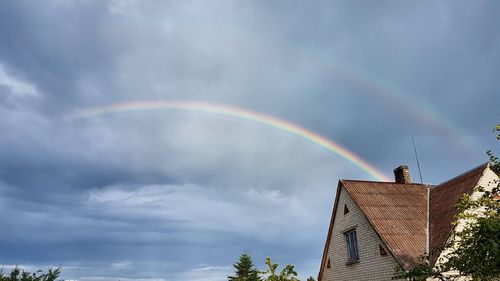 Low angle view of rainbow over trees against sky