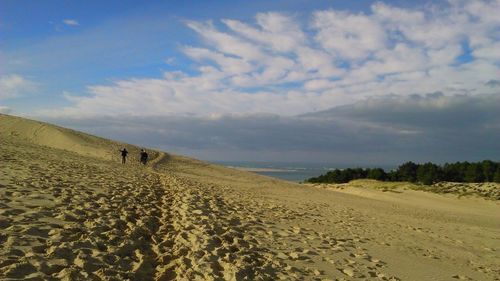 People at dune of pilat against sky