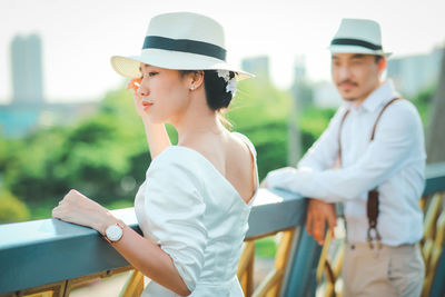 Young couple looking away while standing by railing in city