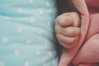 Close-up of baby hand on bed