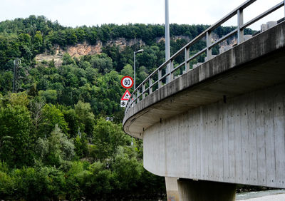 Low angle view of flag amidst trees and bridge against sky