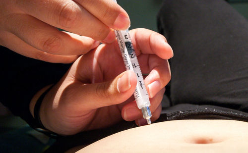 Cropped hands of nurse injecting patient at hospital