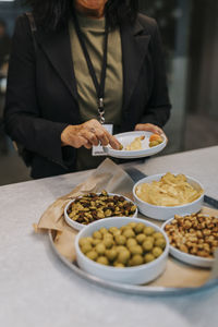 Midsection of senior businesswoman taking snacks in plate during networking event