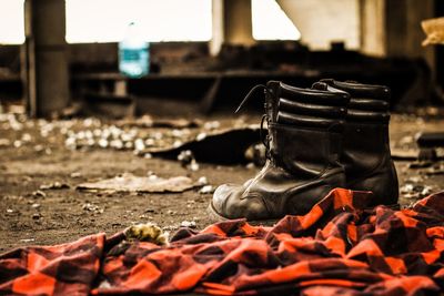 Close-up of old shoes and shirt inside of an abandoned place