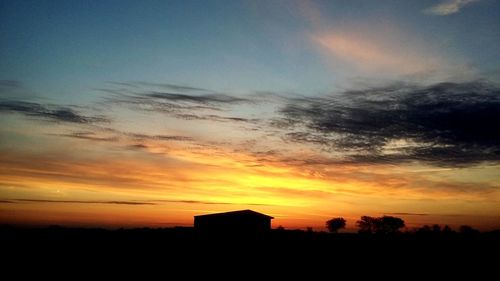 Silhouette houses against sky during sunset