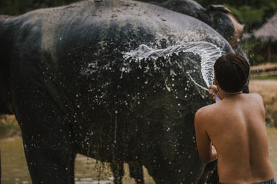 Rear view of shirtless man standing in water